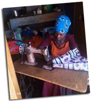 A woman sits at a table using a sewing machine.