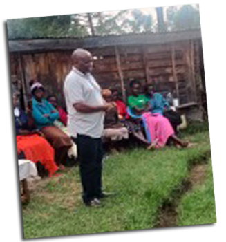 A man is standing teaches a group of women seated in a circle.